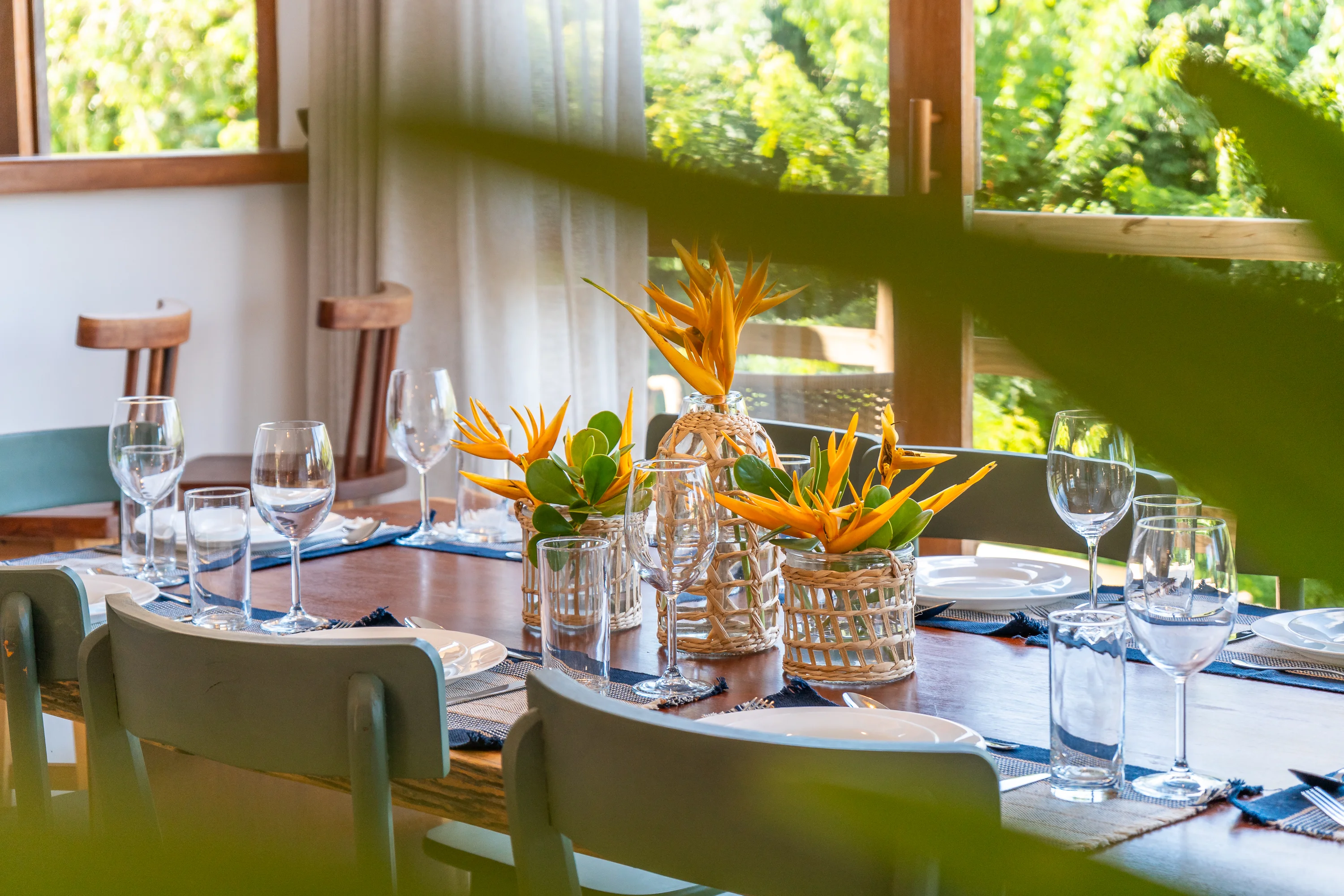 Casa 47 - Esstisch mit Paradiesvogelblumen-Arrangement und Weingläsern