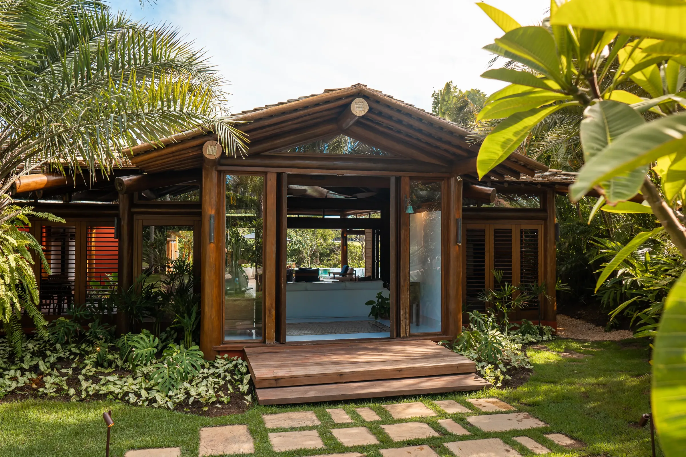 Casa 62 - fachada de madeira com caminho de pedras e jardim tropical