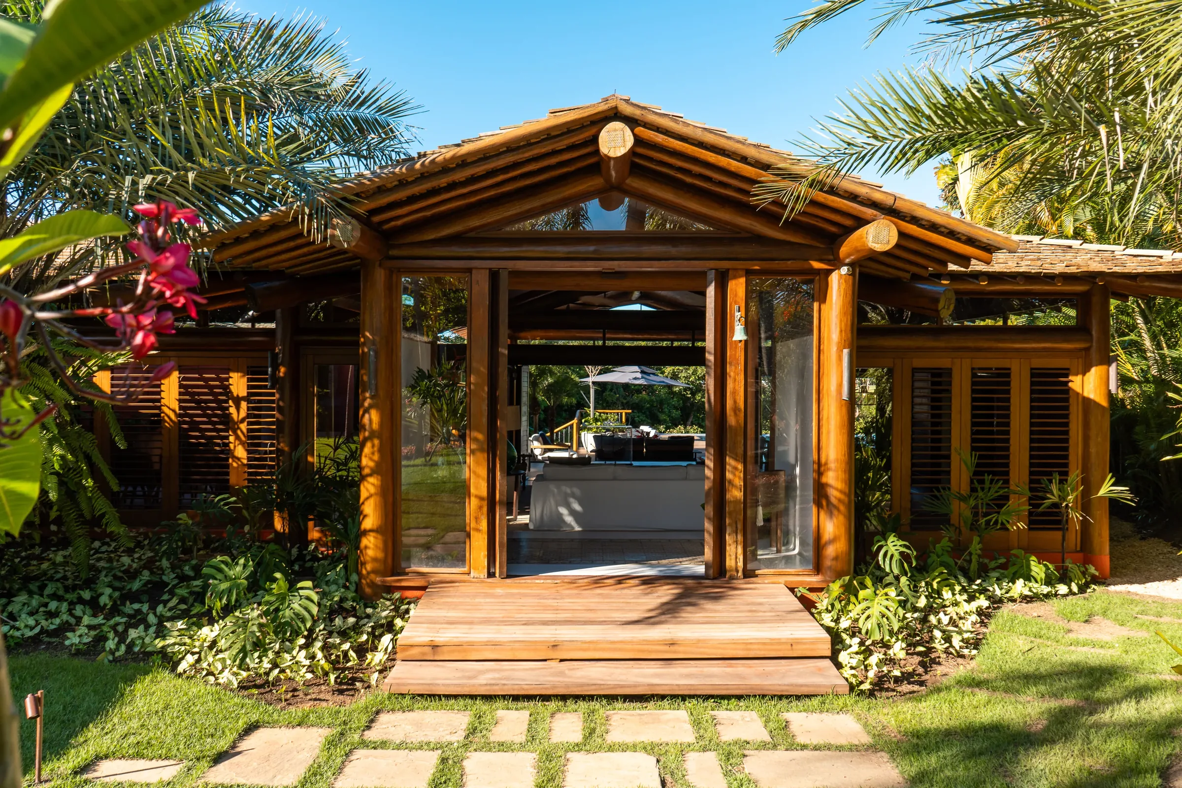 Casa 62 - entrada do pavilhão social, com fachada de madeira entre a vegetação
