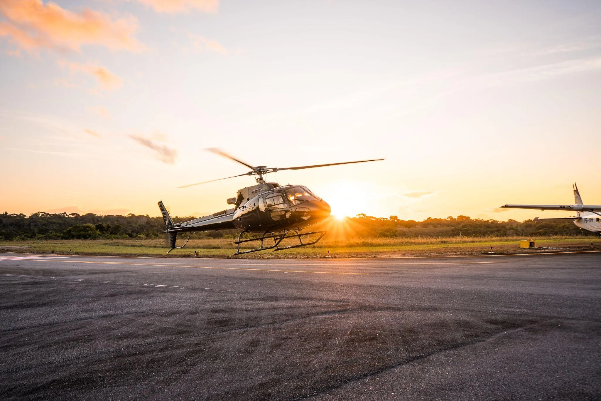 Helicóptero pousado na pista do aeroporto ao pôr do sol
