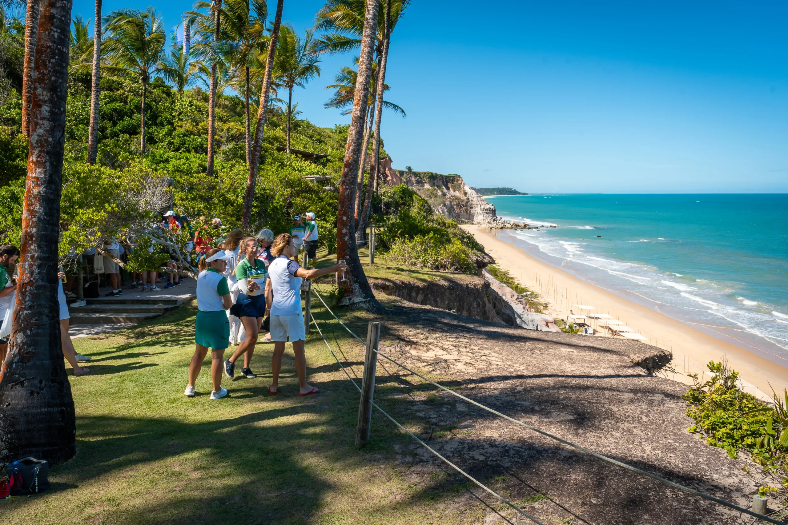 Grupo de golfistas no mirante do campo, com a praia lá embaixo