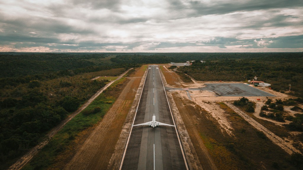 Vista aérea de pista com jato privativo branco e floresta densamente arborizada.